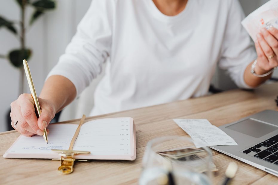 Woman writing notes in her daytime while holding receipts.