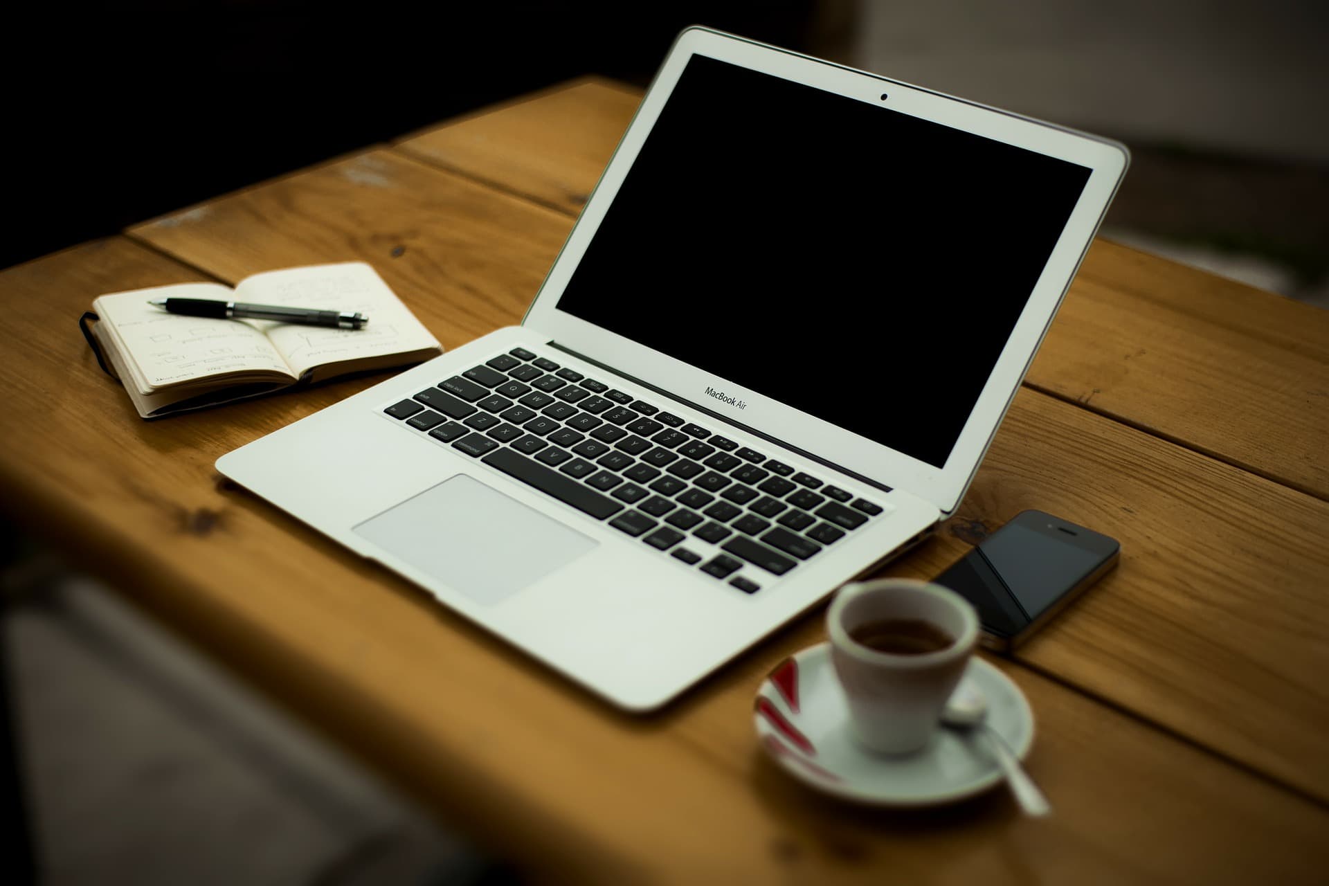 Coffee, notebook and laptop computer on a wood desk