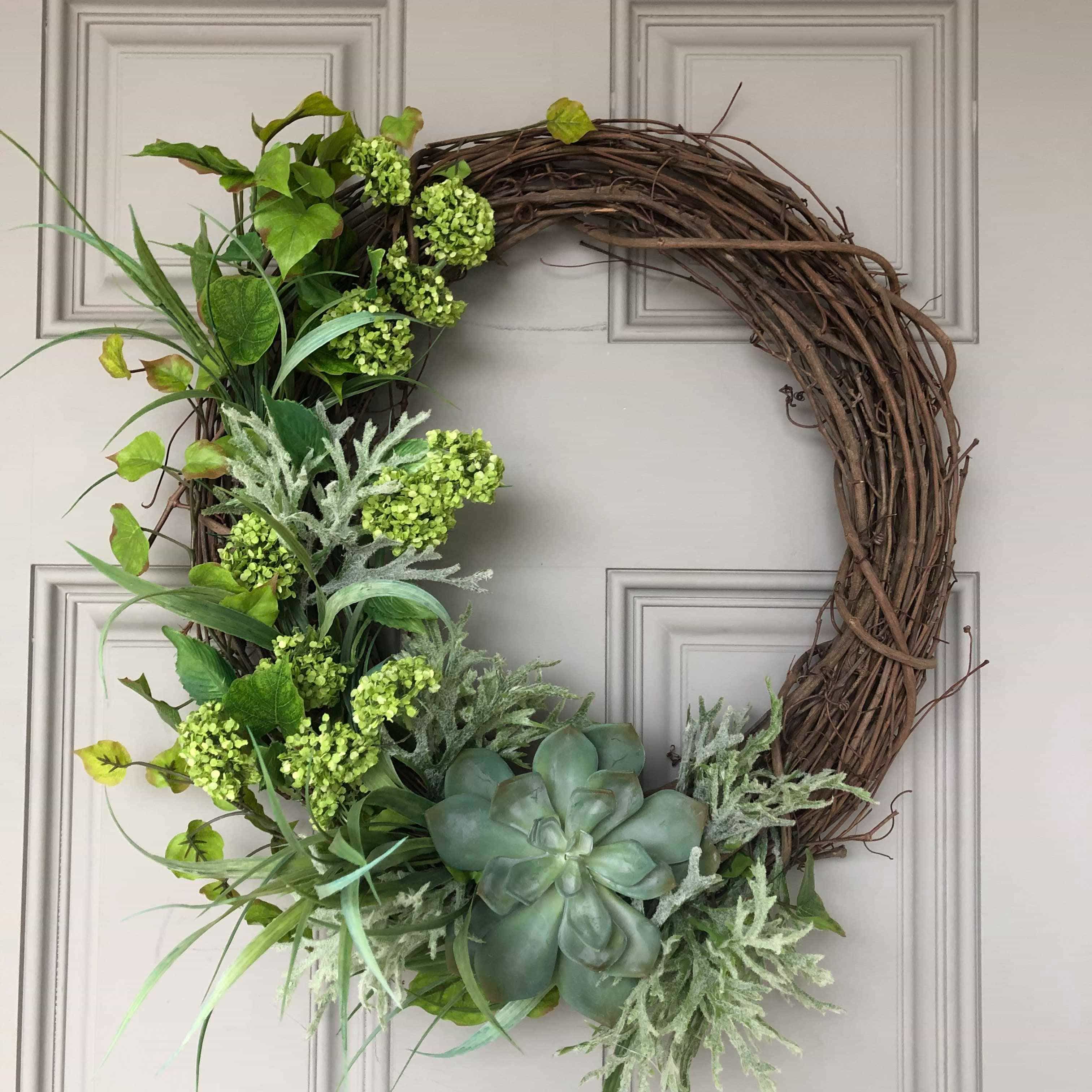 Greenery on a willow wreath on a white door