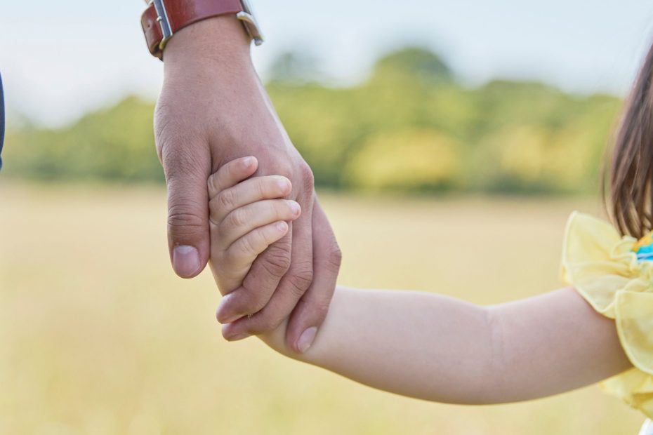 Child's hand resting on top of an adult's.