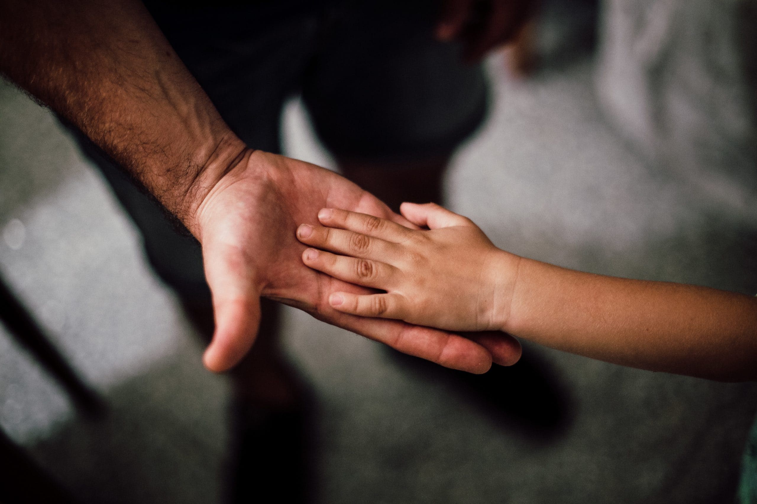 Child's hand resting on top of an adult's.