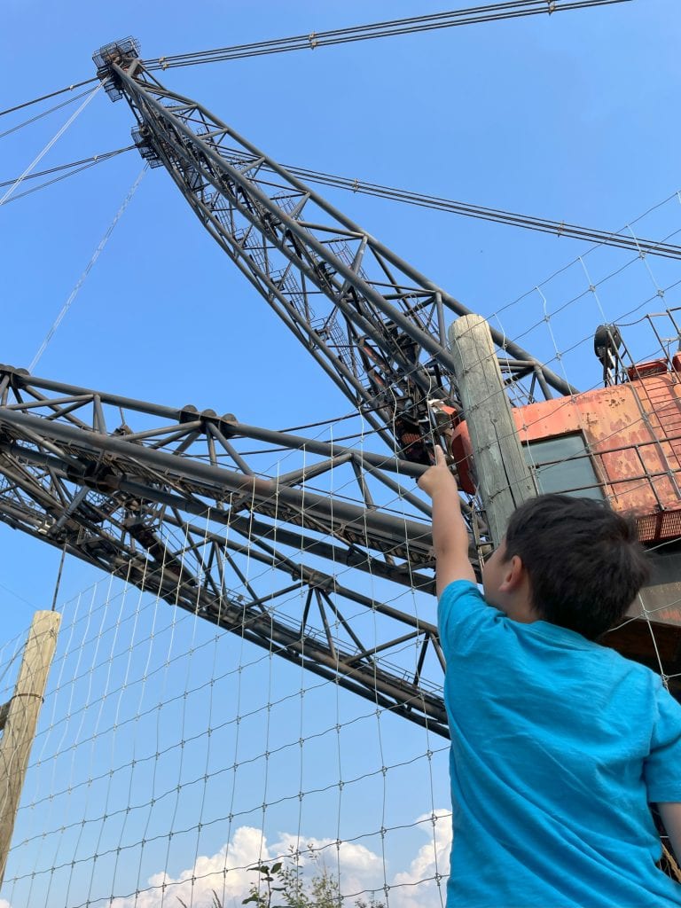 Little boy pointing up to the top of Discover Dragline giant machine at Syncrude Giants of Mining outdoor museum