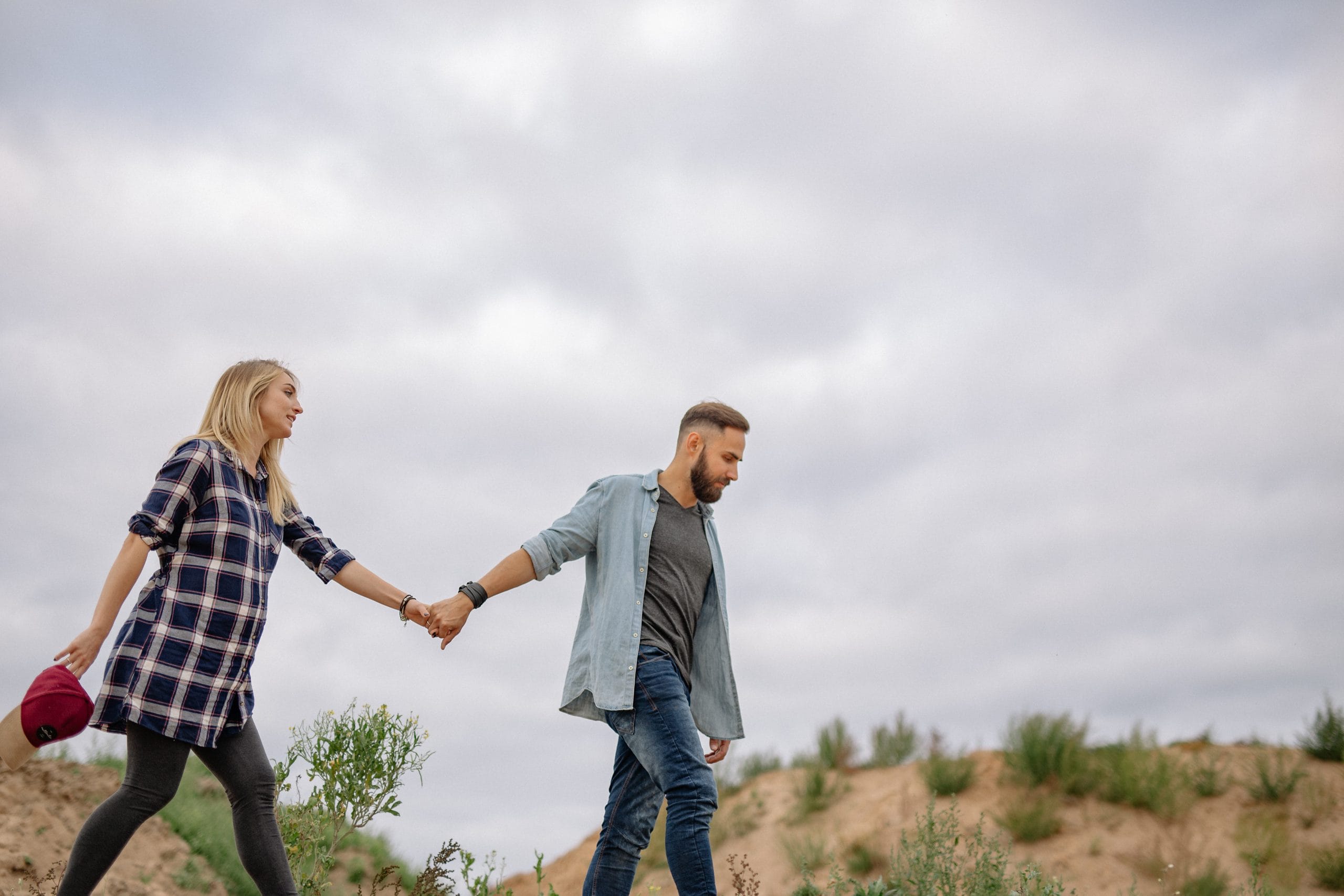 Pregnant couple walking on beach dunes