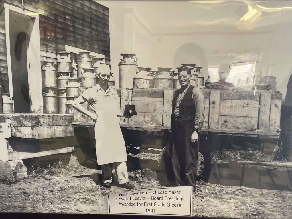 Photo of two men standing in front of a truck filled with milk pails, ready to unload into the Glenwood Cheese Factory. Caption on the photo reads "Ned Davidson - Cheese Maker; Edward Leavitt - Board President; Awarded for First Grade Cheese 1941