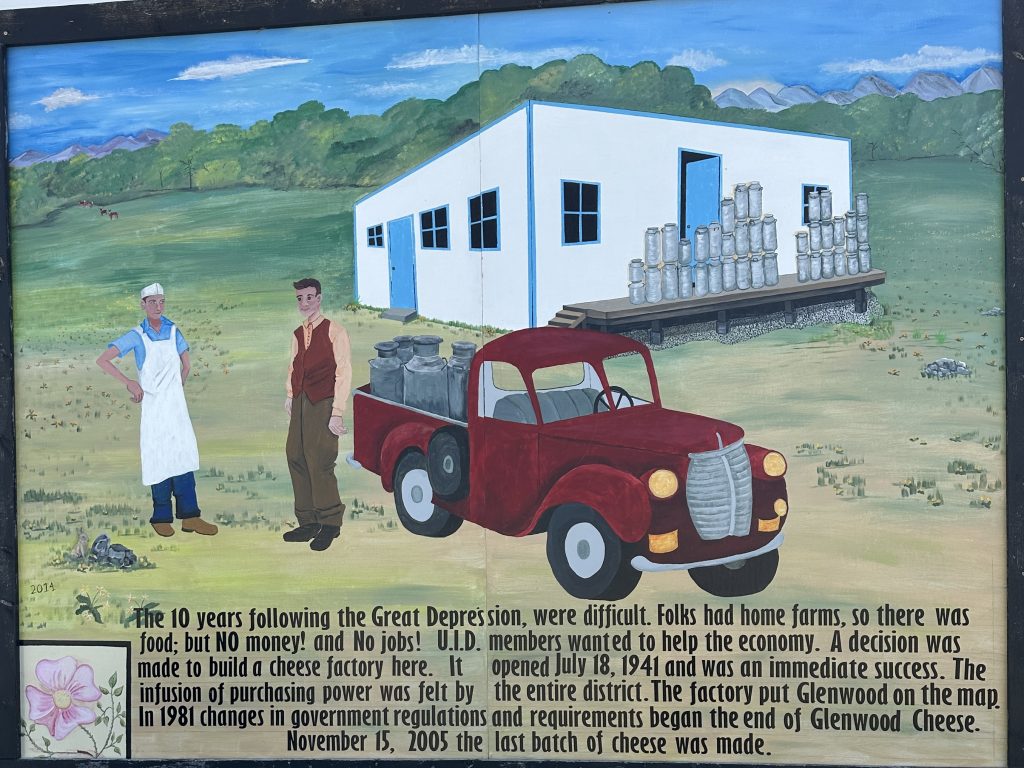 Mural in Glenwood of the Cheese Factory Museum with a red truck in front of it. Text reads "The 10 years following the Great Depression, were difficult. Folks had home farms, so there was food; but NO money! and No jobs! ...D. members wanted to help the economy. A decision was made to build a cheese factory here. It opened July 18, 1941 and was an immediate success. The infusion of purchasing power was felt by the entire district. The factory put Glenwood on the map. In 1981 changes in government regulations and requirements began the end of Glenwood Cheese. November 15, 2005 the last batch of cheese was made."